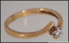 A 9ct gold 375 marked ladies diamond ring having single claw mounted stone to a cross over setting.
