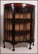 A 1930's Queen Anne revival mahogany demi lune display cabinet raised on ball and claw feet with