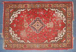 An early 20th century handwoven Iranian rug with central medallion with inset flower on red ground