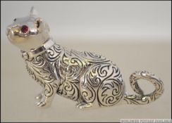 A unusual silver miniature figure of a cat being chase decorated with ruby glass stone eyes.