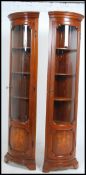A pair of antique style walnut marquetry inlaid bow front corner cabinets of good column shape and