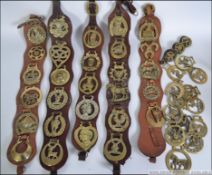A collection of several differing vintage horse brasses on leather Martingales and loose.
