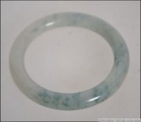 A 20th century green and mutton coloured jade bangle of roundel form. Total weight 59.6g.