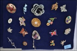 A collection of 20 ladies costume jewellery brooches to include floral, leaf and figural examples.