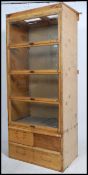 A 1930's shop display cabinet having a series of four up and over glazed doors with recessed