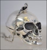 A sterling silver scull vesta of decorative form having hinged centre with safety chain and bar.