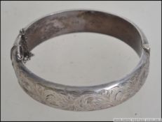 A silver rococo chased hallmarked bangle by SPS&CO bearing Birmingham hallmarks for 1963.