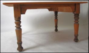 A large late 19th century pine refectory country kitchen dining table being raised on turned legs