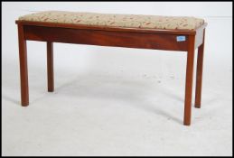 A mid century mahogany piano duet stool raised on squared legs with upholstered hinged seat.