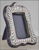 A silver rococo hallmarked miniature picture frame with velour easel backed.