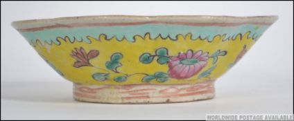 A 19th century Chinese porcelain bowl of lobed form being decorated with stylised foliates on a