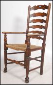 An early 20th century oak North Country ladderback rattan seated armchair raised on turned supports