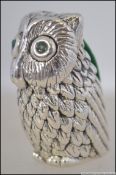 A silver stamped 925 owl shaped pin cushion with emerald eyes having green velour cushion to back.