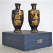 A pair of early 19th century boxed Egyptian brass amphora vases with a black ground and gilt