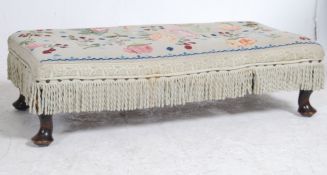 A 1930's tapestry upholstered mahogany footstool raised on stub cabriole legs with pad feet having