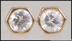 A pair of 9ct gold and cz round cut stud earrings. The posts being stamped 9ct. Weight 0.9g.
