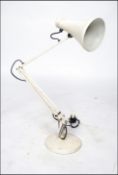 A mid century Industrial Herbert Terry anglepoise desk lamp raised on a white circular terraced