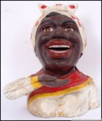 20th century, cast iron money bank of a African ladies head wearing a red spotted scarf. 17cm long.