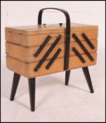 A vintage 1950's metamorphic sewing box raised on tapered legs with multi-sectional hinged top