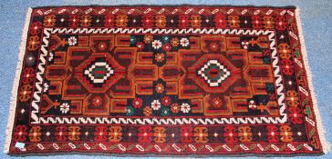 A 20th century Islamic rug of vivid handwoven colours having twin medallions and white borders.