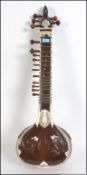 A 20th century Sitar constructed from hardwood and a gourd being decorated with carvings,