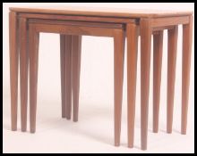 A 1970's G-Plan teak wood nest of tables of Danish influence being raised on shaped supports with