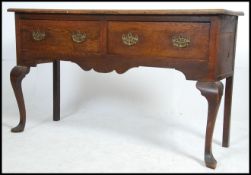 An early 20th century country oak dresser base being raised on cabriole legs with pad feet having