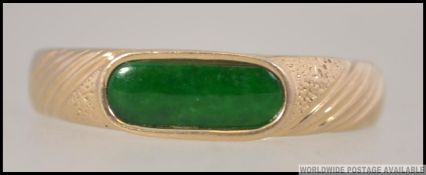 A 14ct gold and apple green jade ring. The ring inset with lozenge shaped jade stone. Size R.