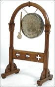An early 20th century carved oak Arts & Crafts gong in the natural form having hanging brass gong