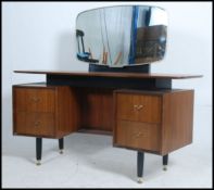 A 1970's G-Plan Librenza teak wood dressing table raised on ebonised supports with suspension