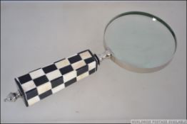 A contemporary large desk top magnifying glass with black and white chequered handle. Measures 22.