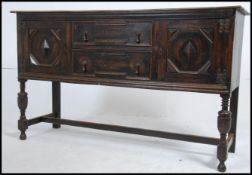A 1920's Jacobean revival oak geometric moulded dresser base being raised on turned legs united by