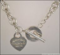 A white metal necklace with heart shaped pendant.