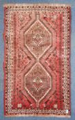 An Islamic Persian rug with red ground having twin medallions uniting to centre having scrolled