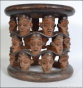 An African Tribal Bamileke stool being raised on masked supports dating to the late 19th century.