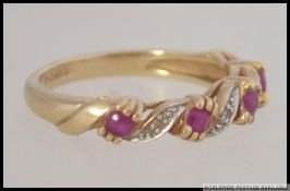 A 9ct gold diamond and ruby ring having inset 3 round cut ruby stones with diamond surrounds.