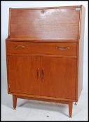 A 1970's teak wood bureau in the manner of Robert Heritage for Archie Shine being raised on tapered