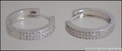 A contemporary pair of silver and cz adorned ladies earrings of creole - hoop form.