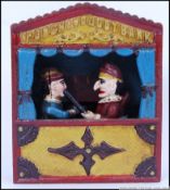 A vintage style, 20th century cast iron money bank of Punch and Judy in their puppet theatre.