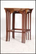 An Edwardian mahogany inlaid nest of tables being raised on squared tapering supports with oval