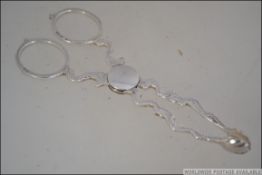 A pair of silver hallmarked sugar nips having oyster shell bowls.