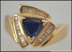 A 14ct gold, sapphire and diamond ring. The triangular diamond with baguette diamond surround.