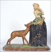 An early 20th century fairground plaster figurine of a maiden and a dog raised on a plinth base