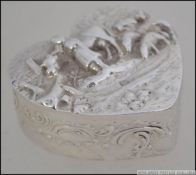 A silver hallmarked pill box in the form of a heart having unusual farming scene cast in relief to