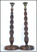 A pair of early 20th century single scone wooden barley twist candlesticks having applied brass
