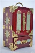 A Chinese hardwood brass and jadeite stone set table cabinet having double doors with small drawers