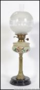 An early 20th century brass and ceramic oil lamp rasied on a two tier circular base with a brass