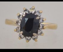A hallmarked 18ct gold sapphire and diamond ring set with a central cushion cut sapphire surrounded