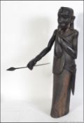 A large carved hardwood wooden sculpture of a African tribal warrior holding a spear and drinking
