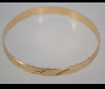 A hallmarked 9ct gold bangle with scalloped edges and diamond cut star engraving. Hallmarked London.